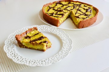 Tasty yellow lemon tart with the dark chocolate on the white table
