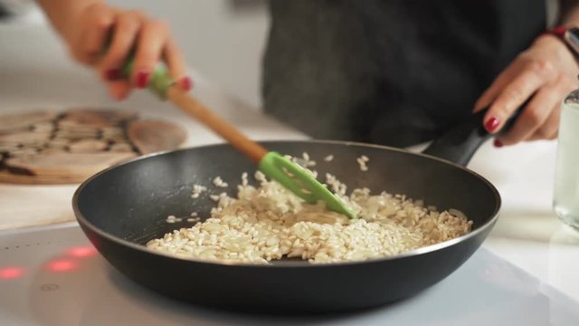 Mid-section shot of hands of unrecognizable female cooking risotto