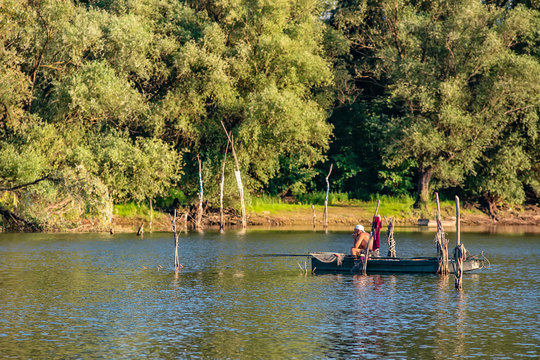 Novi Sad, Serbia - August 04, 2018: Danube island (&Scaron;odro&scaron;) near Novi Sad, Serbia. Fisherman sitting in boat and holding fishing rod.
