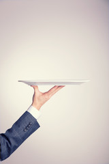 Male arm business suit holding a serving tray plate with copy space.