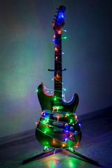 Electric guitar wrapped in colorful garland, the idea of holiday music