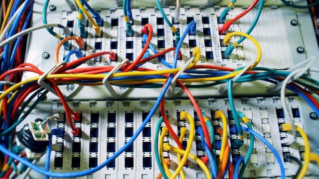 Lots of multicolored cords, wires, cables at a data center. Chaos, mess with wires.