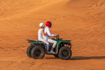 Quad Biking Dubai Adventure Tour – Young copule of tourists having fun on Quad Bike Riding in dunes of Dubai