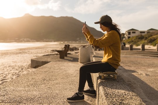 Woman clicking photo with mobile phone near beach