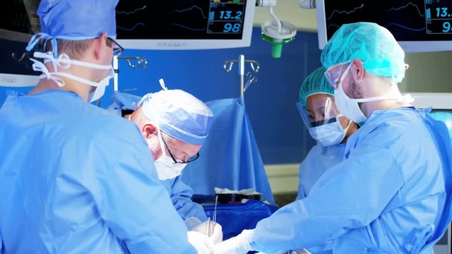 multi ethnic and Caucasian hospital specialist team in scrubs training in the operating theatre in Orthopaedic surgery using tools and modern electronic monitor imaging 