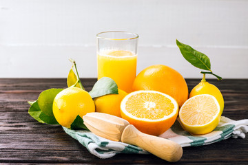 Juicing delicious citruses and glass with juicer on wooden table
