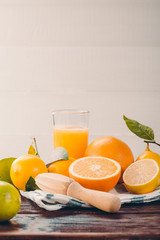 Juicing delicious citruses and glass with juicer on wooden table