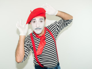 happy male mime .  he dressed in striped t-shirt and red hat, isolated on white background