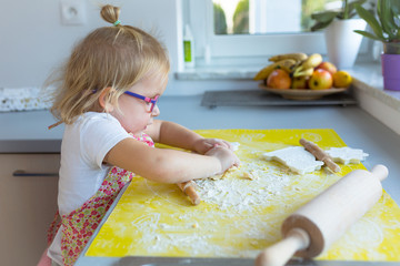 Cute little girl with roller pin preparing Christmas cookies