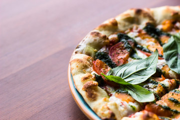 Pizza Margarita or Margherita on wooden table background, top view. Pizza with Tomatoes, Fresh Basil, Mozzarella Cheese, Pepper and Spices close up. Sliced Italian Pizza. 