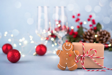Festive background with gift, gingerbread man, Christmas decorations and glasses for champagne