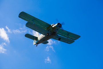 An old plane like a corn duster flying in the sky on a sunny day