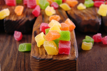 Multicolored dry fruits in a bowl on a wooden table.
