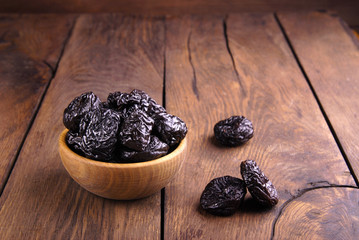 Dry dark plum in a wooden bowl.