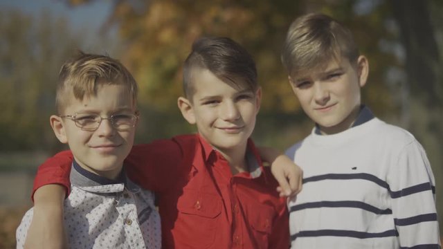 Three young boys smiling and hugging outdoors. Brothers spend time together.