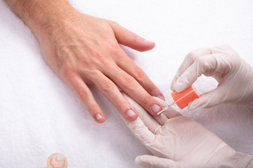 Beautician Applying Nail Oil On Man's Hand