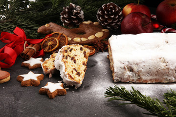 Fototapeta na wymiar Traditional European Christmas pastry, fragrant home baked stollen, with spices and dried fruit. Sliced on rustic table with xmas tree branches and decorations