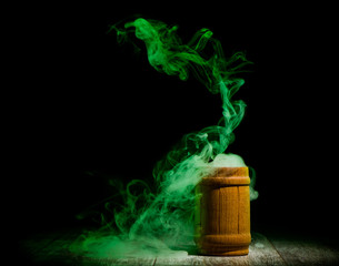 green smoke from wooden jar isolated at dark background