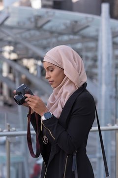 Woman reviewing photos in digital camera at balcony