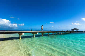 Junge Frau im Bikini steht auf einem Steg in den Malediven
