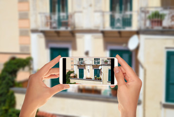 A tourist is taking a photo of typical Italian balcony in Amalfi, Italy on a mobile phone