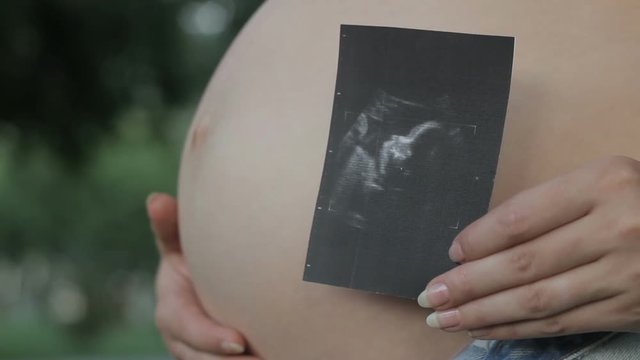 Happy pregnant woman showing heartwarming shot of baby from ultrasound procedure