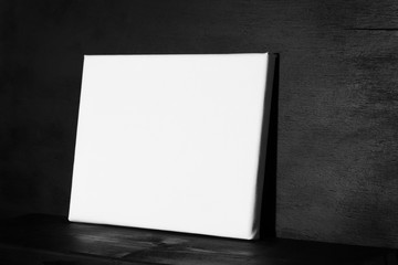 Blank canvas against  a dark black wall. Side view.