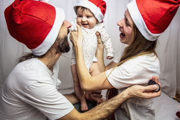 young family with baby having fun with santa hats