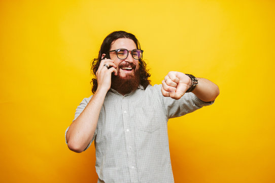 Happy man tlking on phone with friend and lookiing at watch