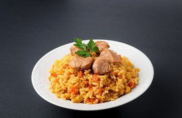 Fragrant Pilau. Pilaf, fried rice with meat and vegetables on a white plate. Isolated on gray.