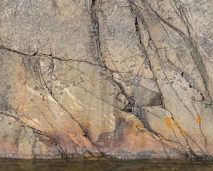 A cracked and lichen encrusted boulder rises from the water