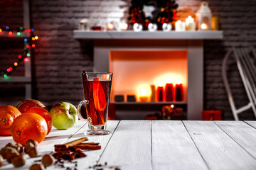 A winter composition on a wooden table in the glow of a fireplace and a Christmas tree decoration on a magical evening   