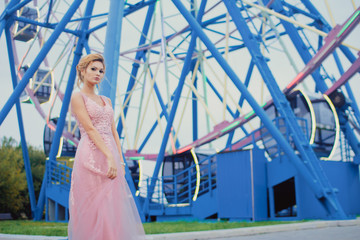 Young beautiful woman in long pink evening dress walking path in park. Fashion style portrait of gorgeous beautiful girl outdoors