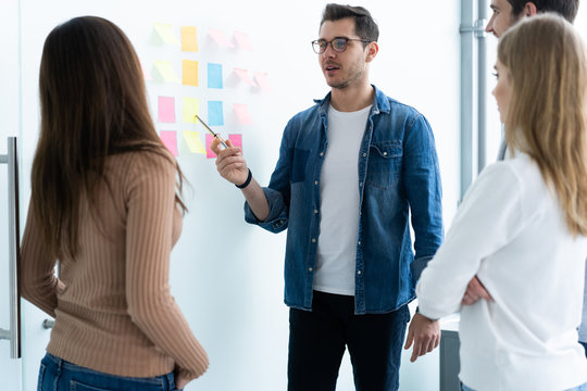 business, education and office concept - business team with flip board in office discussing something.
