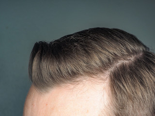 Pulled back hair style on unrecognizable male, towards gray