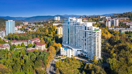 Obraz premium Apartment house white on the background of mountains and forests in the neighborhood bytha in Sochi. Residential area, city area, apartments by the sea.