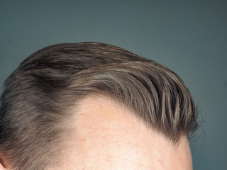 Pulled back hair style on unrecognizable male, towards gray