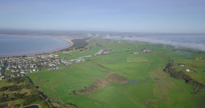Aerial flight over Stanley towards green fields and farms in Tasmania, Australia