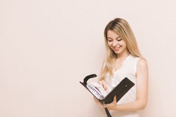 Young attractive blonde businesswoman holds black leather diary. Portrait of a beautiful blonde with a notebook