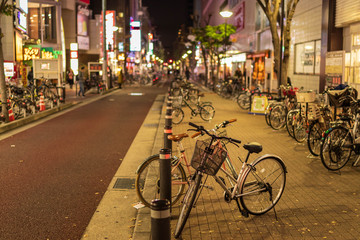 Naklejka na ściany i meble Rows of bicycles line city street at night