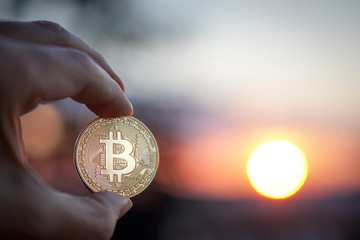 Plakat Hand with Bitcoin at sunset. Selective focus