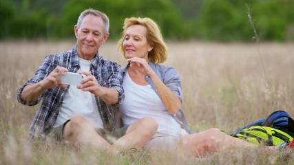 Retired Caucasian American couple having fun using smart phone taking photo in the countryside outdoors 