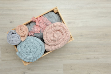 Wooden box with warm knitted plaids of pink and blue color. Close up