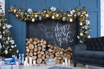 Beautiful decor of the holiday happy new year with prepared wood for the fireplace and the inscription of a happy new year, written in chalk