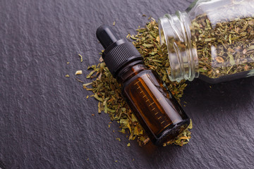 dried tarragon and essential oil on a dark stone background