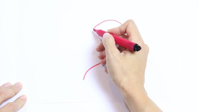 Woman's hand drawing red heart with marker on white table