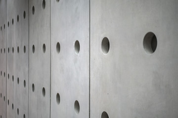 Modern grainy concrete wall with plenty of regular holes on the wall