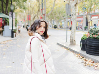 Beautiful young brunette woman looking and smiling in sunny autumn day. Outdoor fashion portrait of glamour young Chinese business stylish lady. Emotions, people, beauty and lifestyle concept.