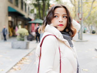 Fototapeta premium Beautiful brunette woman looking back with hands on head in sunny autumn day. Outdoor fashion portrait of glamour young Chinese business stylish lady. Emotions, people, beauty and lifestyle concept.