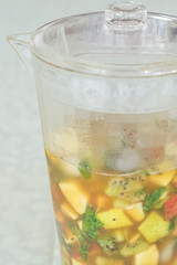 Jug of drink with fruits, ice and pimm's on white background